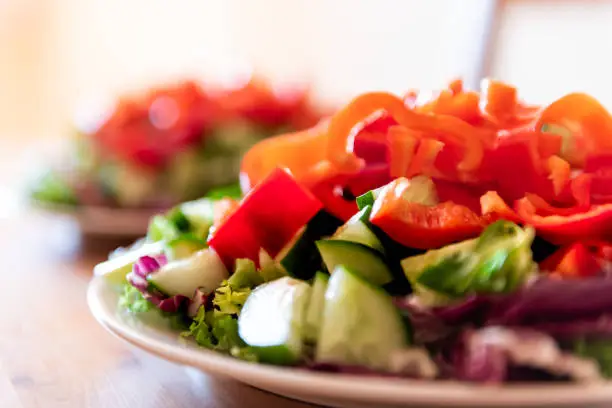 Healthy vegan vegetarian lunch or dinner green vegetables red bell pepper salad with nobody and two plates in bokeh background