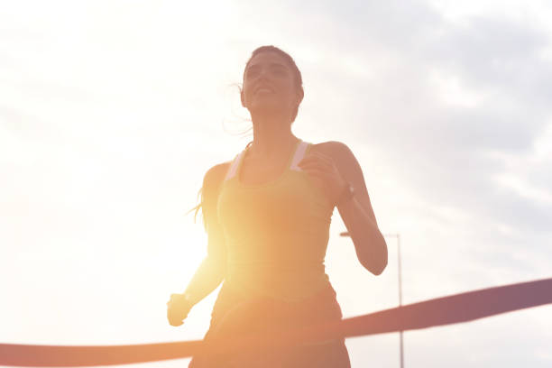 Sporty girl finishing the race Portrait of attractive brunette with beautiful smile full of energy running to the finish line of race finish line photos stock pictures, royalty-free photos & images