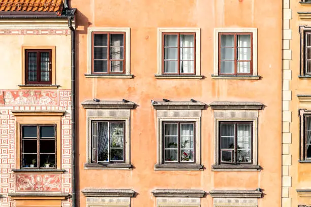 Warsaw, Poland old town market square with closeup of historic street town architecture windows pattern of red orange yellow light color