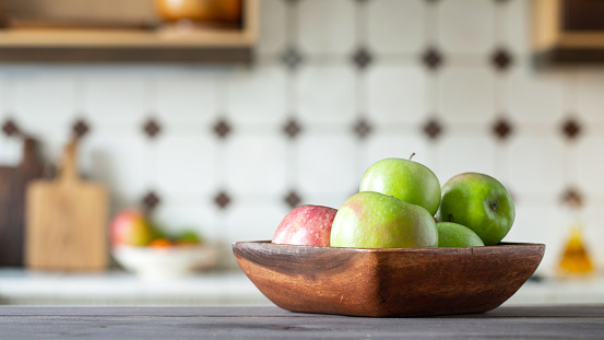Ripe juicy green apples in a wooden bowl on the kitchen table in the and rustic.