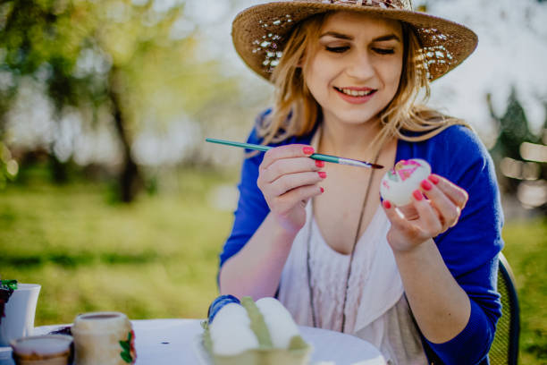 istock Young woman coloring Easter eggs on a sunny day 1138047029