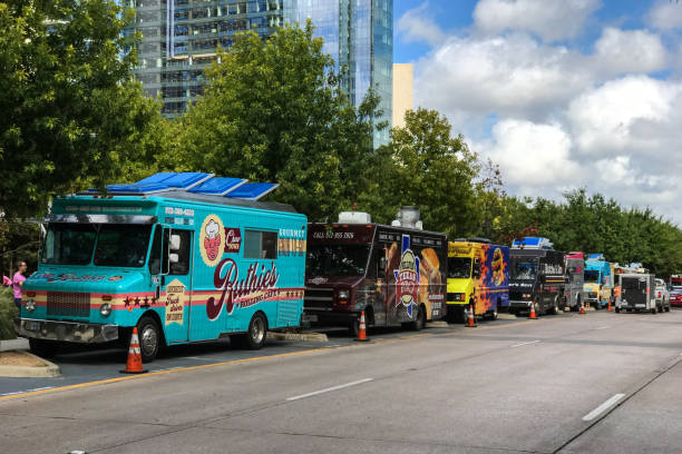 Colorful Food Trucks Parked In A Row On Dallas Street Dallas, TX, USA - October 6, 2018: Several colorful food trucks are parked all in a row on a street beside a public park on a Saturday on October 6, 2018 in Dallas, TX. restaurant labor union stock pictures, royalty-free photos & images