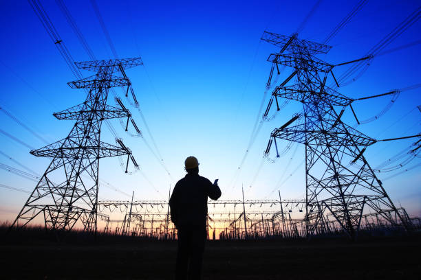istock Electricity workers and pylon silhouette 1138051098