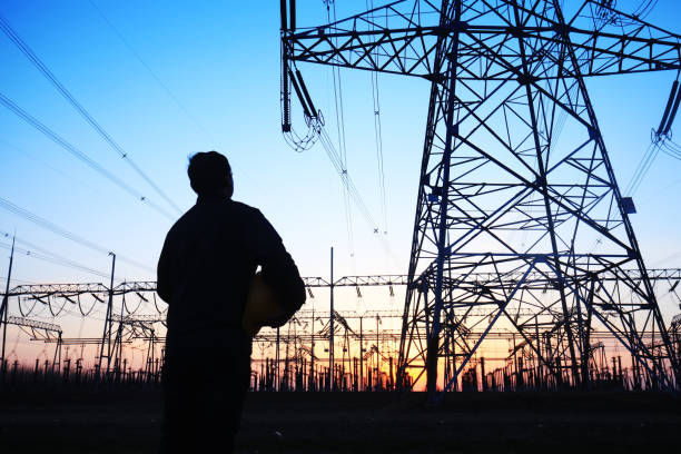 istock Electricity workers and pylon silhouette 1138051102