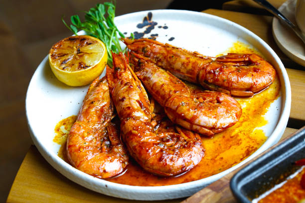 Plate of grilled prawns with sauce and vegetable sides