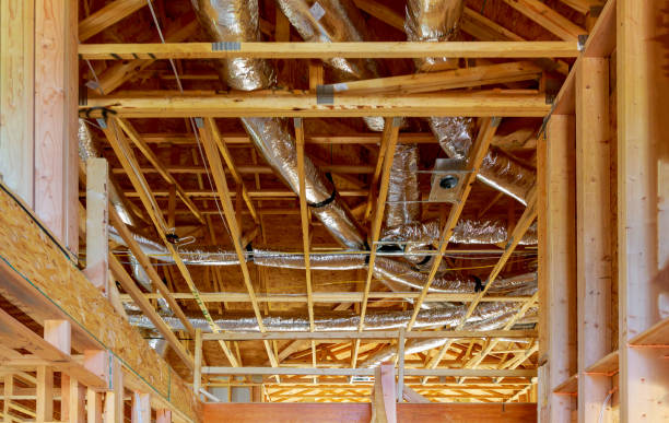 Ventilation pipes in silver insulation material hanging from the ceiling inside new building.