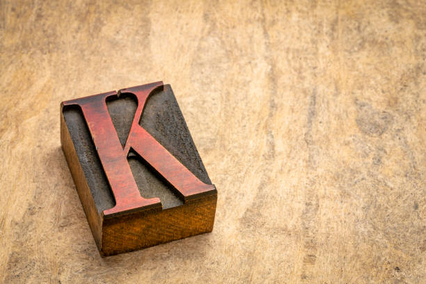 letter K in vintage letterpress wood type printing block against textured bark paper with a copy space