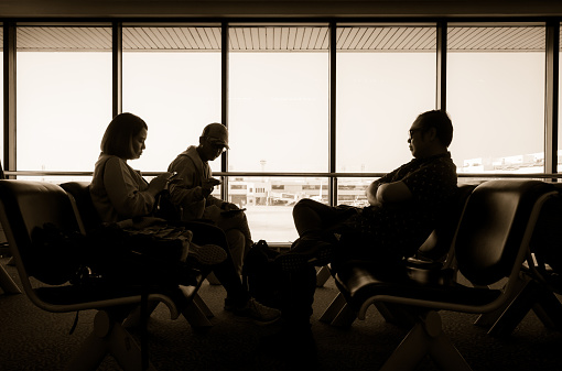 Silhouette of passengers sit at waiting room in airport terminal