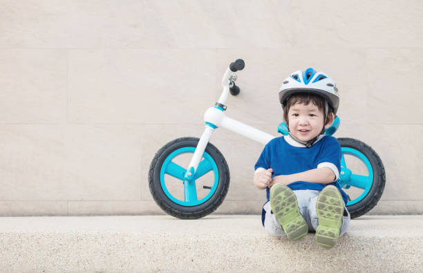istock Closeup happy kid with smile face sit on marble stone floor with bicycle onstone wall textured background with copy space 1138075539