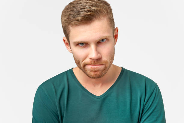 istock Puzzled man keeps lips pressed, has frustrated facial expression, frowns face in displeasure, being deep in thoughts. Male dressed in casual outfit, models over white wall 1138076456