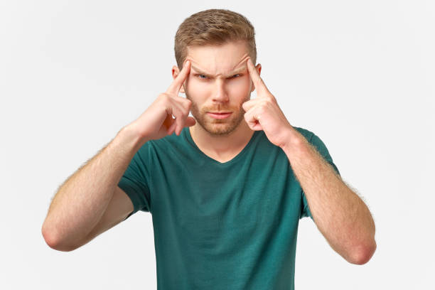 istock Upset man looks at camera, keeps hands on temples, raises eyebrows model against white wall in studio 1138076525