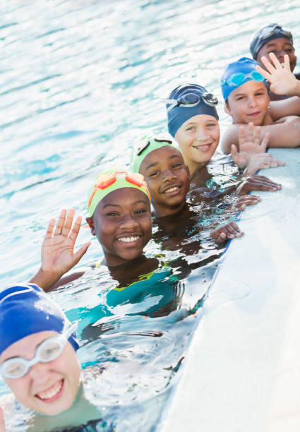 istock Multi-ethnic children on swim team in pool, waving 1138079559