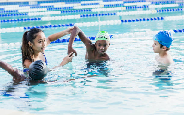 istock Young woman giving swim lessons to multi-ethnic group 1138080209