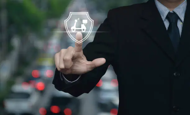 Businessman pressing motorcycle with shield flat icon over blur of rush hour with cars and road in city, Business motorbike insurance concept