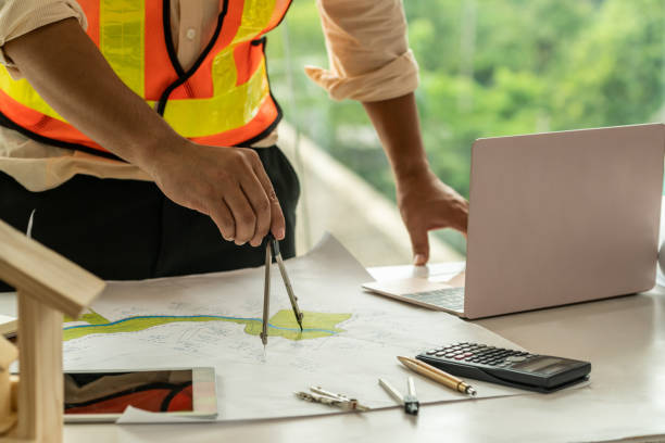 istock Young man architect or engineer working at desk with designer equipment to make interior design at workplace. Real estate business and civil engineering concept. 1138081613