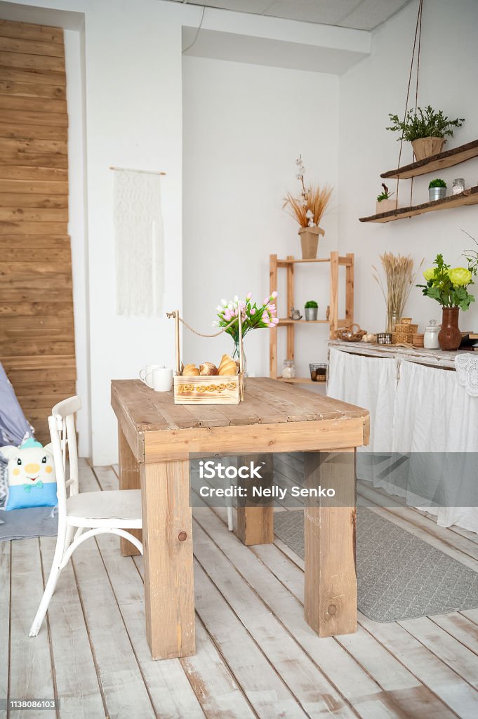Summer kitchen interior in rustic style. Bright kitchen with a wooden table. Spring flowers and bread in a basket on the table in the kitchen House Stock Photo