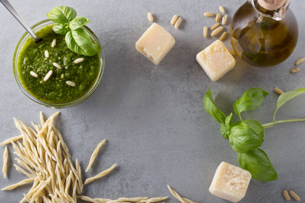 Raw trofie pasta and a glass bowl with pesto souace stock photo