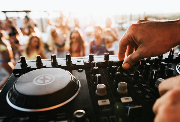 Close up of unrecognizable DJ playing music on turntable during summer beach party.