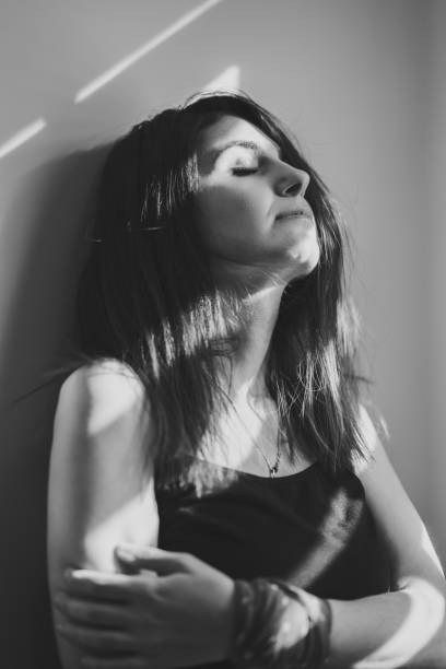 istock Girl stands alone at the window blinds.Black and white concept. 1138097349