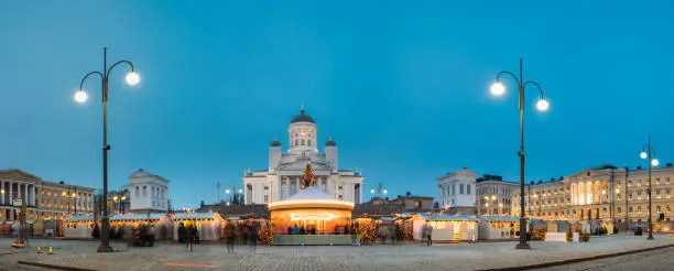 Photo of Helsinki, Finland. Market On Senate Square With Holiday Carousel And Famous Landmark Is Lutheran Cathedral In Winter Night