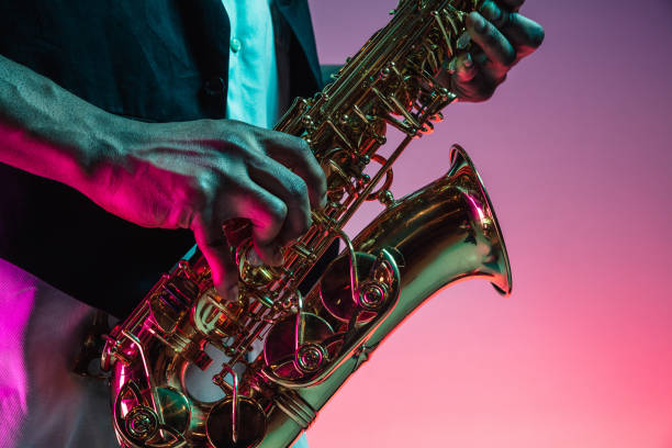 African American jazz musician playing the saxophone. African American handsome jazz musician playing the saxophone in the studio on a neon background. Music concept. Young joyful attractive guy improvising. Close-up retro portrait. saxophone stock pictures, royalty-free photos & images