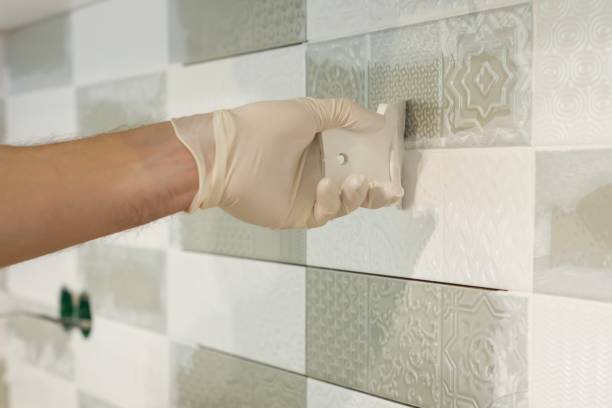 Closeup of tiler hand rubbing tile, Installing and grouting decorative finishes in environments with an high aesthetic value. Two-component, decorative, acid resistant epoxy grout Closeup of tiler hand rubbing tile, Installing and grouting decorative finishes in environments with an high aesthetic value. Two-component, decorative, acid resistant epoxy grout. hand with a plaster spatula stock pictures, royalty-free photos & images