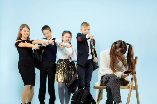 menina que senta-se sozinho na cadeira e que sofre um ato do bullying. - bullying child teasing little boys - fotografias e filmes do acervo