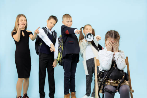 menina que senta-se sozinho na cadeira e que sofre um ato do bullying. - bullying child teasing little boys - fotografias e filmes do acervo