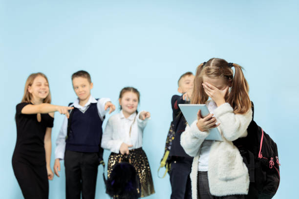 маленькая девочка, стоящая одна и страдающая от издевательств. - bullying child teasing little boys стоковые фото и изображения