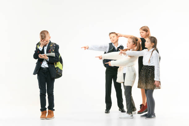 маленький мальчик, стоящий один и страдающий актом издевательств. - bullying child teasing little boys стоковые фото и изображения