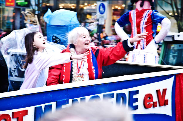 membros felizes de "kg blau-rot dortmund mengede ' 79 ev." (incl uma criança e uma mulher idosa) que executam e que jogam doces no desfile de dortmunder rosenmontag (carnaval de segunda-feira de rosa) em dortmund kampstrasse-alemanha - laughing street party carnival beauty - fotografias e filmes do acervo