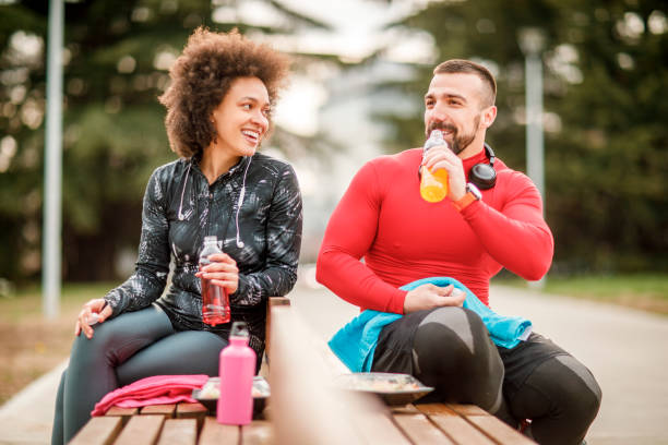 Young athletic couple hydrating themselves while taking a break after exercising in a city park