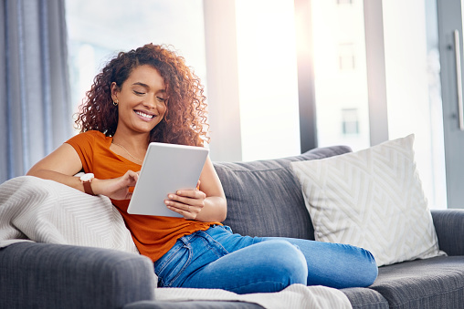 Shot of a young woman using a digital tablet on the sofa at home