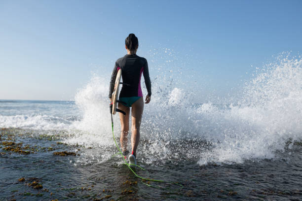 istock Woman surfer with surfboard going to surf 1138124175