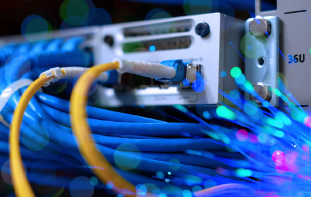 Yellow fiber optic cable with lighting of fiber optics and high speed network router switch in a technology data center room. widescreen stock photo