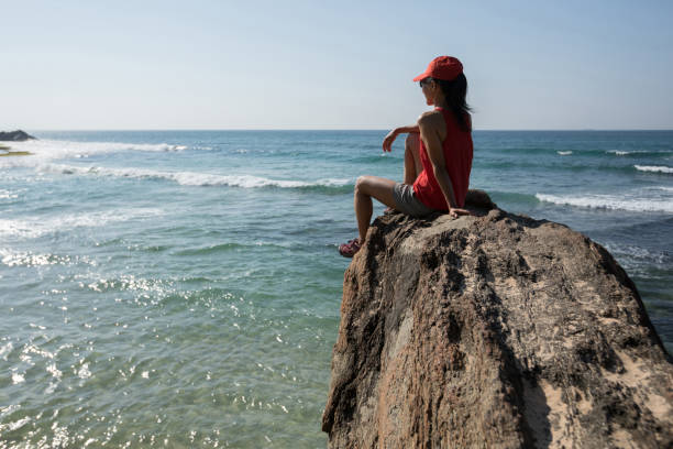 istock Brave woman sit on the cliff edge at seaside 1138126661