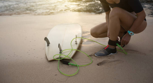 istock female surfer fastening leash across leg before going to surf 1138127051
