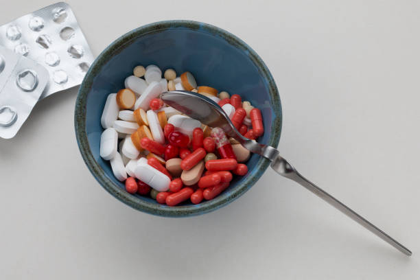 istock Assorted pharmaceutical pills in a bowl with a spoon and blank blister packs on light background 1138128608