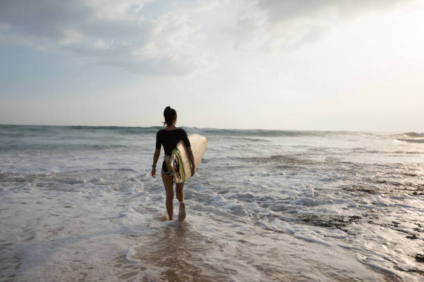 istock Woman surfer walking on the beach going to surf 1138129969