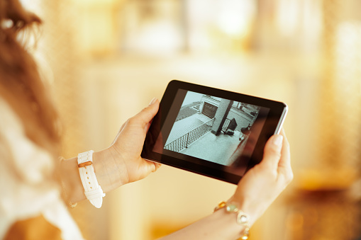 Closeup on tablet PC with video from security camera in hands of modern housewife at home.