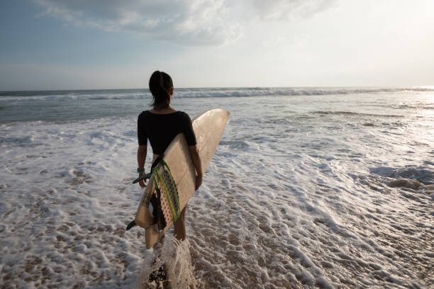 istock Woman surfer with surfboard going to surf 1138130346