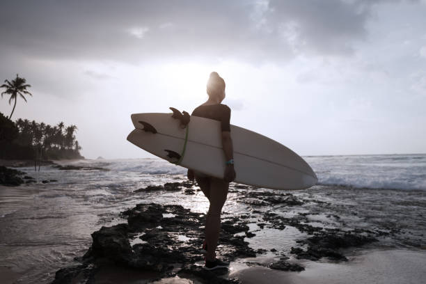 istock Woman surfer with surfboard going to surf 1138130412