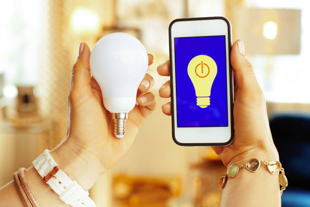 istock Closeup on phone with smart home app and smart lamp in hands 1138131076