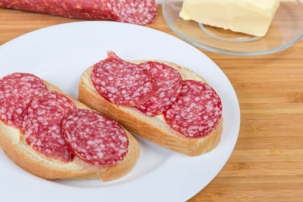 istock Open sandwiches with salami on bamboo cutting board against ingredients 1138131109