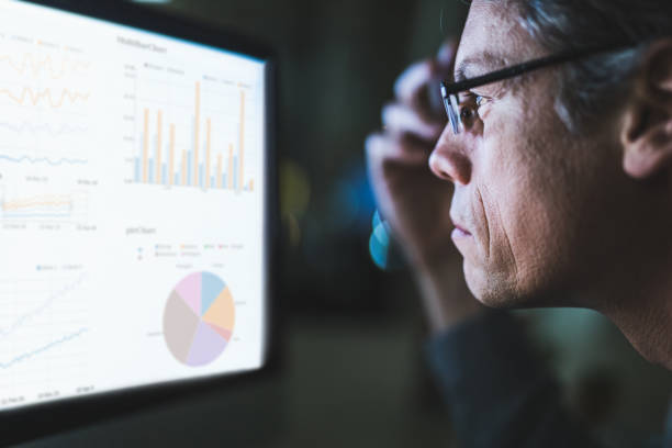 istock Profile view of a businessman analyzing charts on a computer late in the office. 1138131857