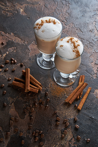 Coffee latte on a wooden rustic table with coffee beans and cinnamon