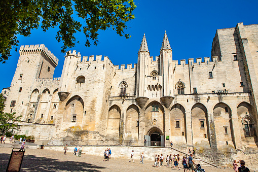 Avignon, France - June 26, 2012: Facade of the Palace of the Popes (Palais des Papes) in France. In front of the photo is a square with almost no people.