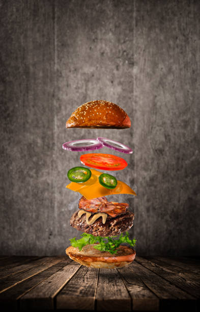 Tasty hamburger with flying ingredients on dark background