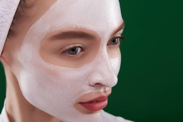 istock Beautiful young woman using facial cleansing mask 1138136699