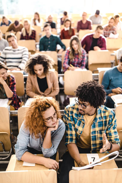 étudiants de collège coopérant tout en lisant une conférence sur une classe. - amphitheater photos et images de collection